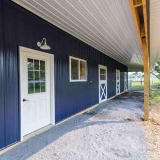 Entry door, aluminum, finished in white powder coat on a barn with blue metal siding.