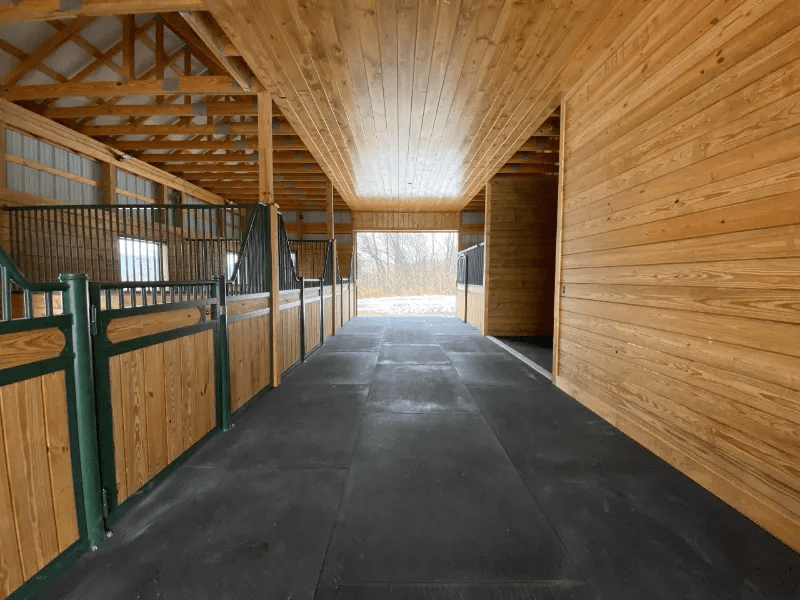 A hallway in front of horse stalls