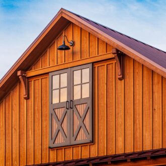 Wooden barn with sliding loft doors in rustic finish under a clear sky.