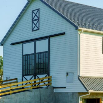 Modern barn with black and white sliding loft and exterior doors, featuring crossbuck design and large windows.