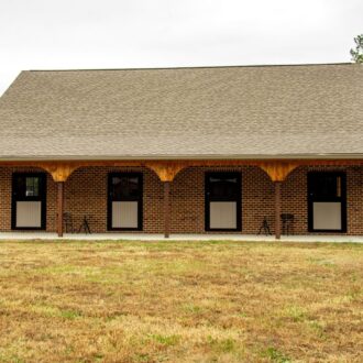 Brick building with four Dutch doors, featuring protective stall grills and customizable finish options.
