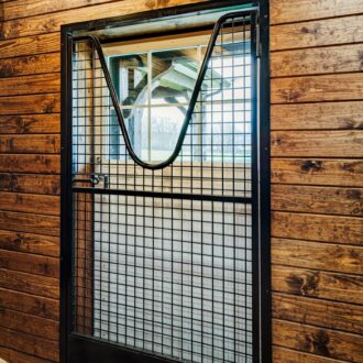 Black mesh dutch door with protective grill set in a wooden frame, showcasing a rustic finish option.
