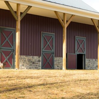 Elegant red and gray carriage doors on a barn with protective stall grills and finish options.