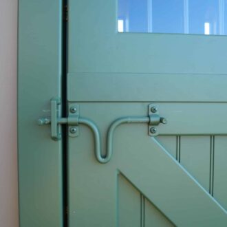 Green Dutch door latch with protective stall grill option, showcasing custom finish and durable hardware.