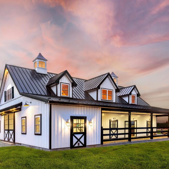 Barn with sliding barn doors and Dutch doors at sunset. Features black finish and protective stall grills.