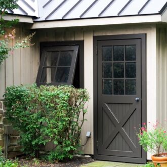 Dutch door and awning window with dark finish in garden setting, featuring panel design and versatile opening options.