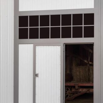 Gray and white entry door with upper windows, showing open entry to barn interior. Durable and customizable design.