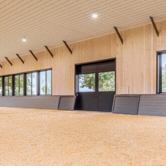 Interior of horse arena with sliding doors and arena windows.