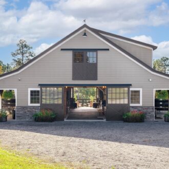 A barn with sliding barn doors, featuring Dutch windows and customizable finish options in a rural setting.