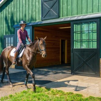 A rider exits a barn