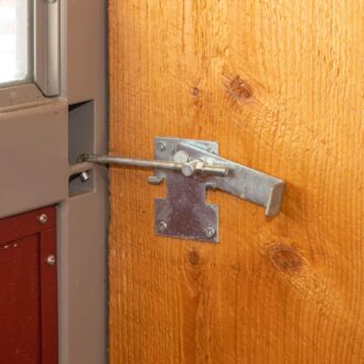 Close-up of a sliding barn door jamb latch on wood, showcasing sturdy metal hardware and a rustic finish.