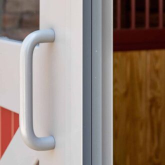 Close-up of barn door handle with red and white finish, showcasing durable metal and wood texture.