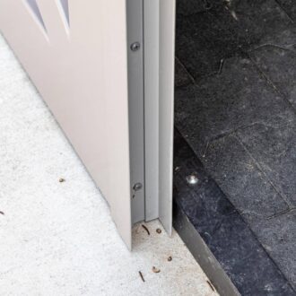 Close-up of a sliding barn door bottom, showcasing durable construction and sleek finish on concrete flooring.