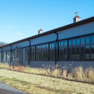 Modern arena with large sliding barn doors and arena windows in a sleek black finish, featuring durable materials.