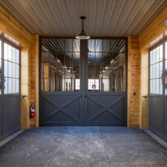 Sliding barn doors with protective stall grills, wood finish, and metal accents. Ideal for spacious, rustic entryways.