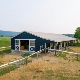 Blue barn with sliding barn doors, protective stall grills, and Dutch windows, in a scenic countryside setting.