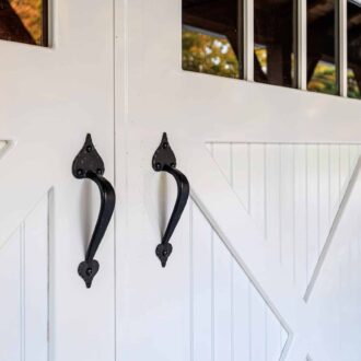 White carriage doors with black handles and upper windows, featuring customizable finish options and sturdy construction.