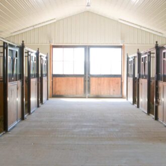 Elegant stable with sliding doors, protective stall grills, wood finish, black accents, ample natural light.