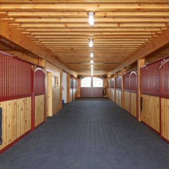 Wooden stable with sliding doors, featuring protective stall grills and natural finish.