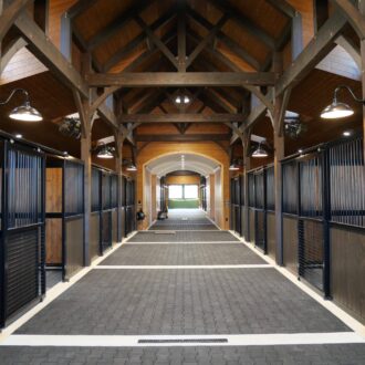 Luxurious horse stable with sliding doors, featuring protective stall grills and dark wood finish options.