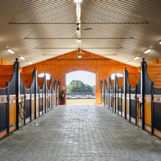 A walkway with line of custom European stall fronts with sliding doors and protective grills.