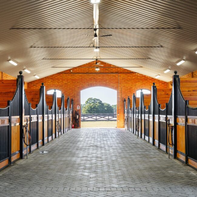 A walkway with line of custom European stall fronts with sliding doors and protective grills.