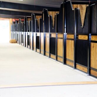 Horse stables with sliding doors, protective stall grills in black and wood finish, bright entry door view.