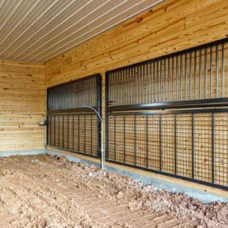 Metal horse stall gates with protective grills in a wood interior. Options: mesh grills, black finish.