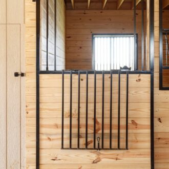 Wooden sliding stall door with protective stall grill in a pine finish. Ideal for stables, providing security and style.
