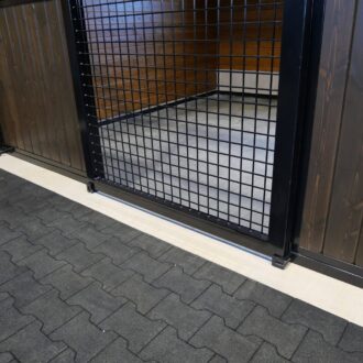 Barn stall with sliding door and mesh grill, featuring dark wood finish. Ideal for barns needing secure, stylish access.