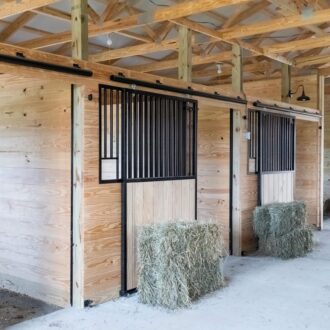 Sliding stall doors with full grills and solid wood inset, mounted on wood stall fronts.