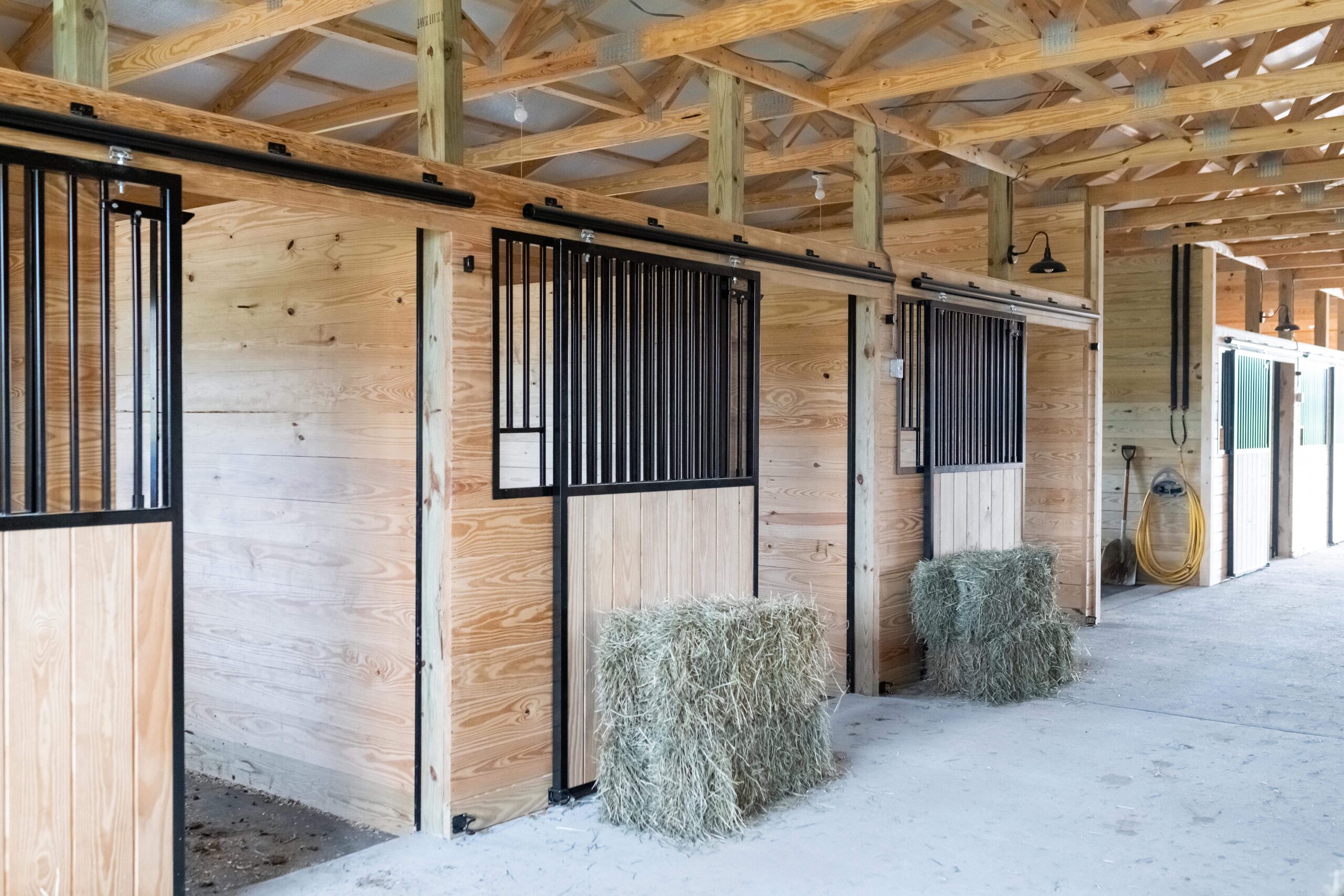 Sliding stall doors with full grills and solid wood inset, mounted on wood stall fronts.