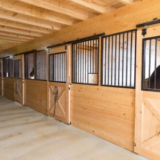 A row of stalls with sliding doors and custom stall fronts.