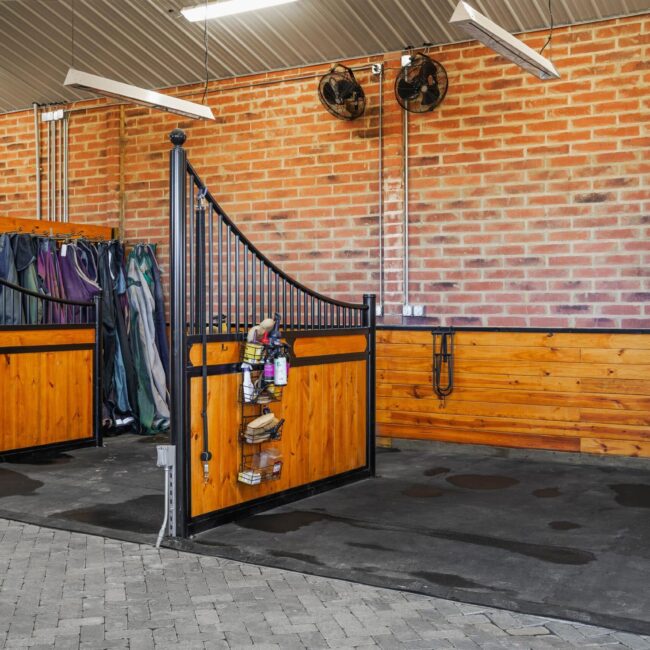 Horse stable with wooden and metal stall fronts and partitions, featuring protective grill options.