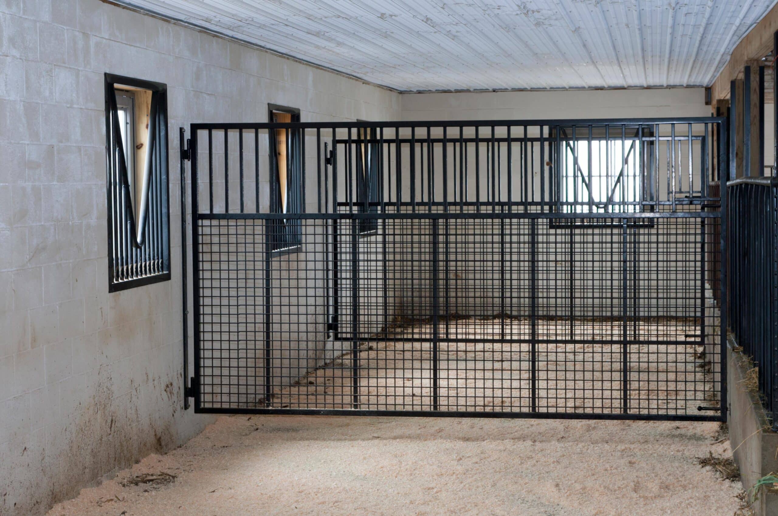 Stall with protective mesh grill, awning windows, and customizable finish, ideal for entry or sliding barn doors.