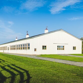 Large arena with sliding doors and arena windows, surrounded by greenery and featuring cupolas on the roof.