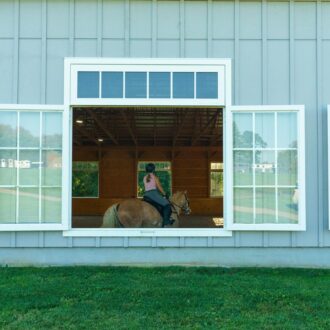 Large, open arena windows on barn, rider inside. Custom finishes available. Perfect for ventilation and natural light.
