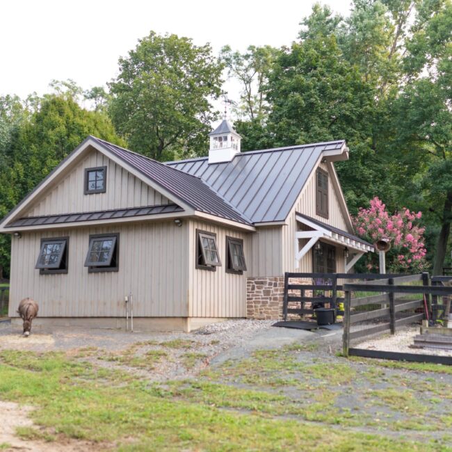 Rustic barn with dark awning windows, sliding loft doors, and carriage door. Features protective grill options.