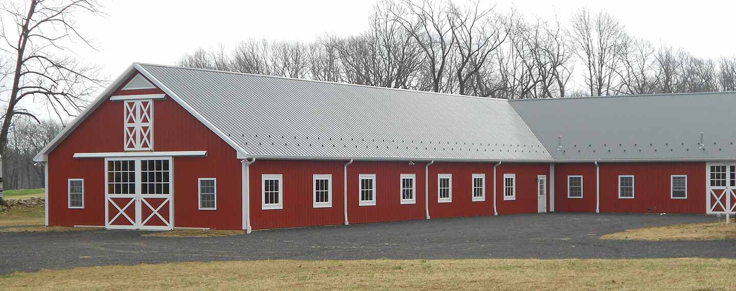 Red barn with sliding barn doors, carriage doors, dutch windows, and awning windows. Metal roof and white trims.