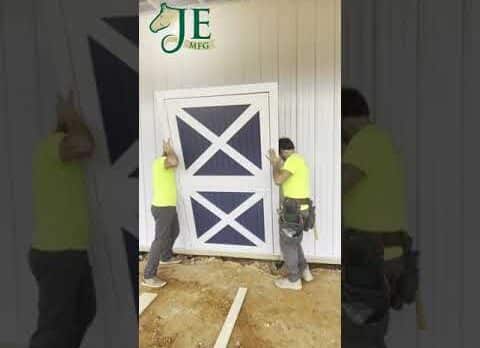 Workers install a white and blue Dutch door with X-pattern, showcasing customizable finish options.