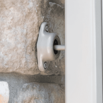 Close-up of a suction cup door catch, showcasing sturdy metal hardware mounted on a stone wall for secure functionality.