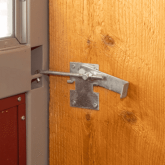 Close-up of a mounted jamb latch on a barn door, highlighting quality and durability.