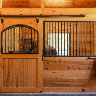 Wooden stall with sliding stall door and protective grill, showcasing many J&E stall accessories.