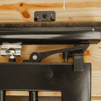 Close-up of a sliding barn door track and hardware on wooden wall. Durable black finish offers sleek functionality.