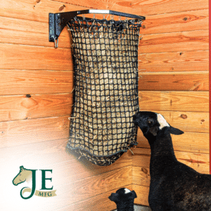 Black mesh haynet hay feeder on wooden wall. Ideal for easy feeding in stalls for horses, sheep, and other livestock.