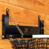 Black mesh haynet hay feeder on wooden wall with chain suspension. Ideal for barn use.