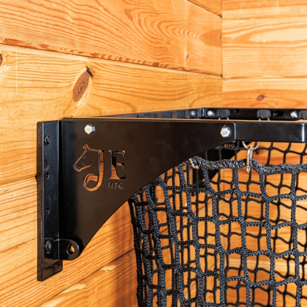 Black mesh haynet hay feeder on wooden wall. Ideal for easy feeding in stalls for horses, sheep, and other livestock.