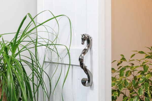 Decorative horse-head handle in a dark chrome finish on a white sliding barn door.
