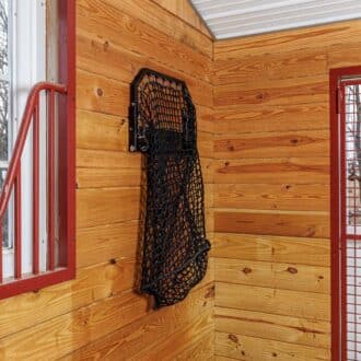 EZ-fill haynet on wooden wall, surrounded by red mesh stall grill and large window panel, natural finish.