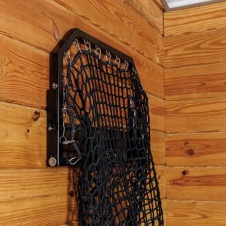 Black EZ-fill haynet with protective stall grill on wooden stable wall, ideal for slow feeding.
